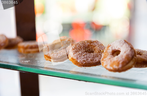 Image of close up of sugared donuts on showcase shelf