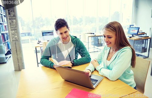 Image of happy students with laptop and books at library