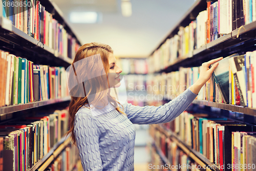 Image of happy student girl or woman with book in library