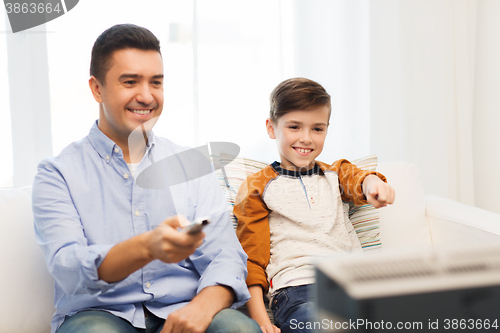 Image of smiling father and son watching tv at home