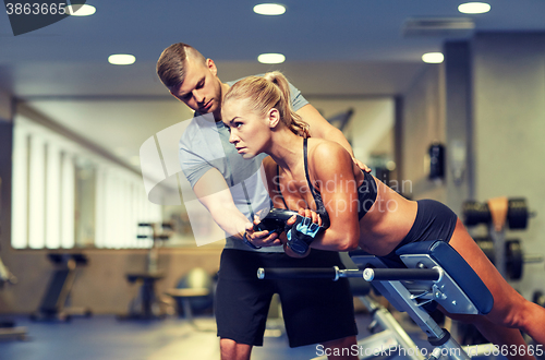 Image of woman with personal trainer flexing muscles in gym