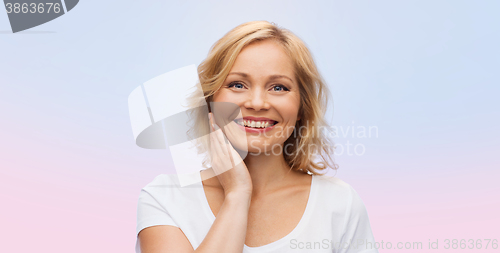 Image of smiling woman in white t-shirt touching her face