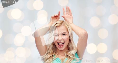 Image of happy smiling young woman making bunny ears