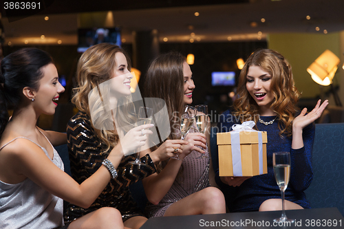 Image of happy women with champagne and gift at night club