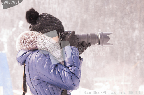 Image of Young girl photographed in the winter in a snow storm on a SLR camera with telephoto lens