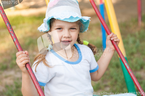Image of Five-year girl in summer panama rides on a swing