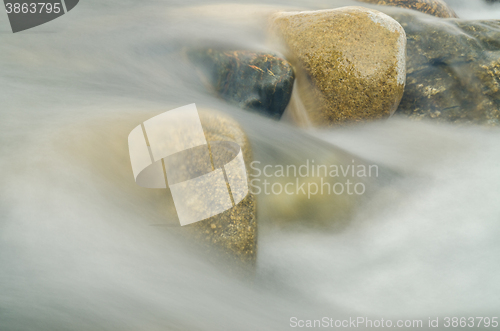 Image of Current between the stones of the river, blurred by a slow shutter speed