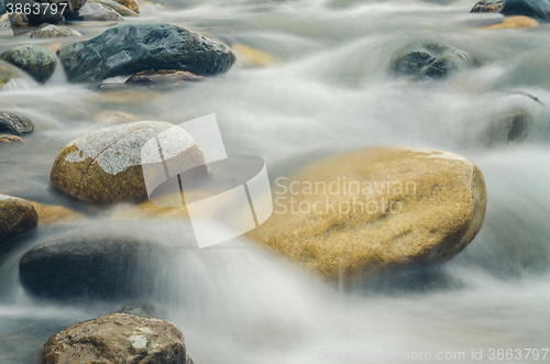 Image of Stone is in the mountain river, blurred by a slow shutter speed