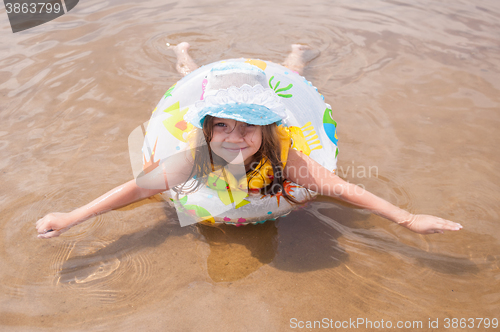 Image of  Little girl in the shallows lying on his stomach in the inflatable ring outstretched arms and legs