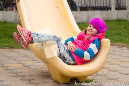 Image of Five-year girl moved down from the hill sits cheerfully on it