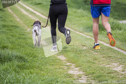 Image of Young man and woman running with dog