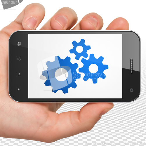 Image of Business concept: Hand Holding Smartphone with Gears on display