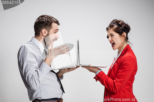 Image of The young businessman and businesswoman with laptops on gray background