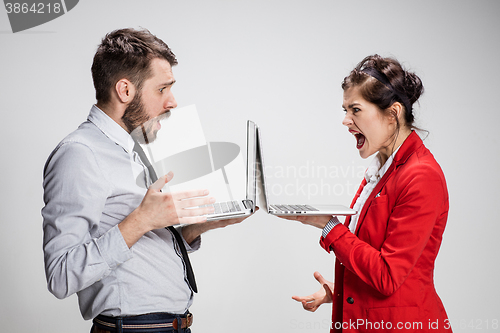 Image of The young businessman and businesswoman with laptops on gray background