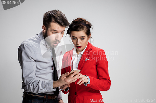 Image of Business concept. The two young colleagues holding mobile phone on gray background