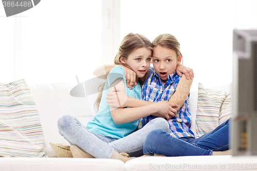 Image of scared little girls watching horror on tv at home