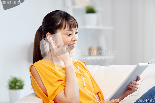 Image of happy asian woman with tablet pc and earphones