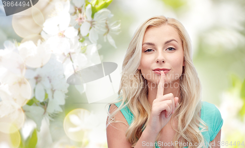 Image of beautiful young woman holding finger at her lips