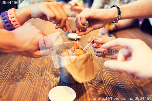 Image of close up of people hands taking cheese balls