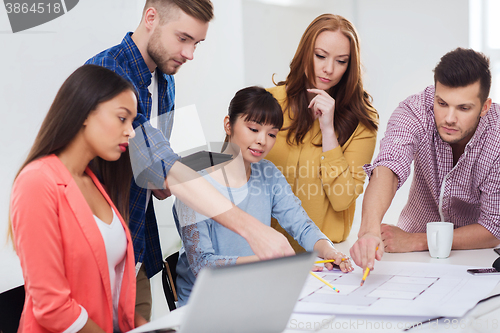 Image of creative team with blueprint working at office