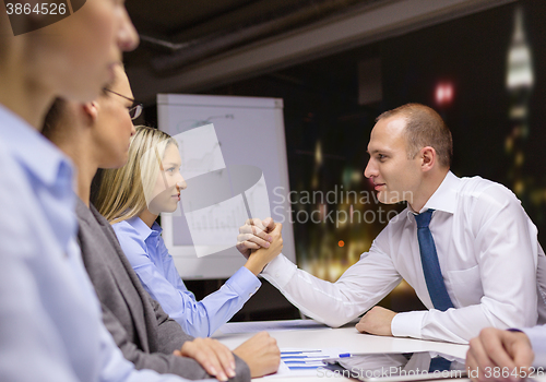 Image of businesswoman and businessman arm wrestling