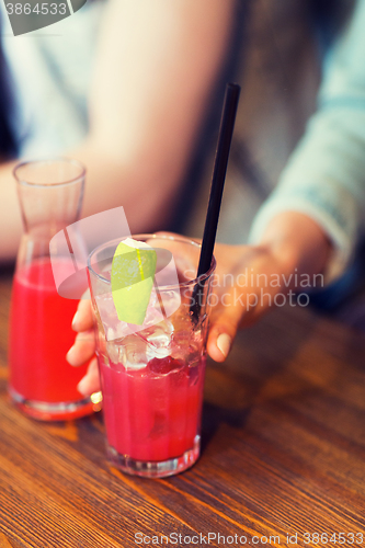 Image of close up of hand with cocktail or juice and straw 