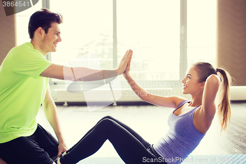 Image of woman with personal trainer doing sit ups in gym