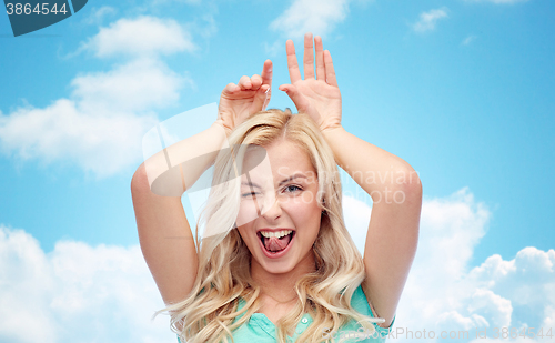 Image of happy smiling young woman making bunny ears