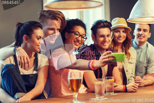 Image of happy friends with smartphone taking selfie at bar