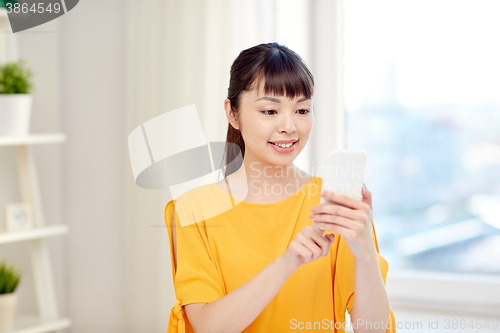 Image of happy asian woman with smartphone at home
