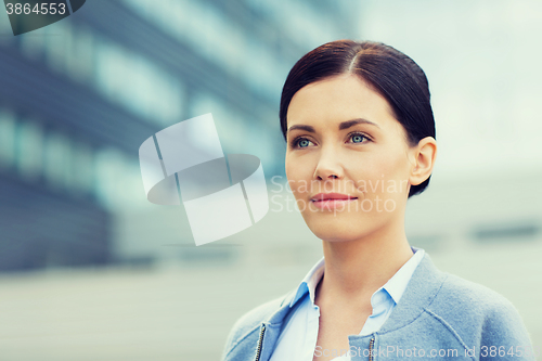 Image of young smiling businesswoman over office building