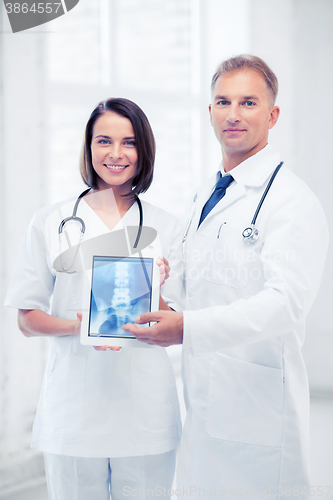 Image of two doctors showing x-ray on tablet pc