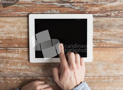 Image of close up of male hands with tablet pc on table