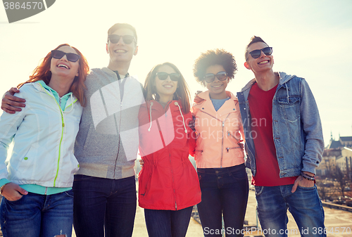 Image of happy teenage friends in shades hugging on street