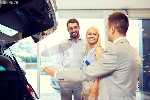 Image of happy couple with car dealer in auto show or salon