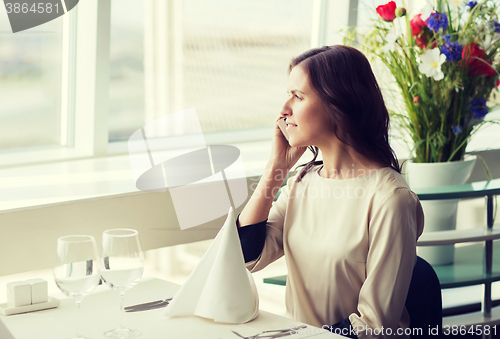 Image of happy woman calling on smart phone at restaurant