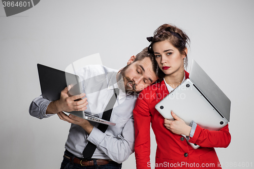 Image of The young businessman and businesswoman with laptops  posing on gray background