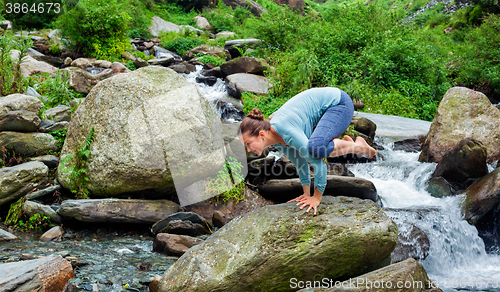 Image of Woman doing Kakasana asana arm balance outdoors