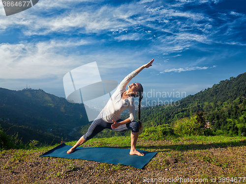 Image of Woman practices yoga asana Utthita Parsvakonasana outdoors