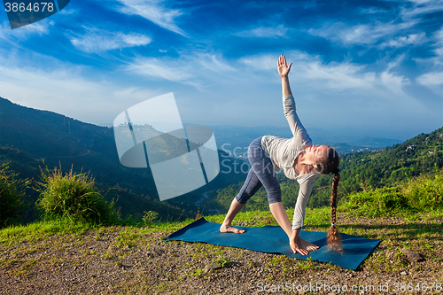 Image of Woman doing Ashtanga Vinyasa yoga asana Parivrtta trikonasana