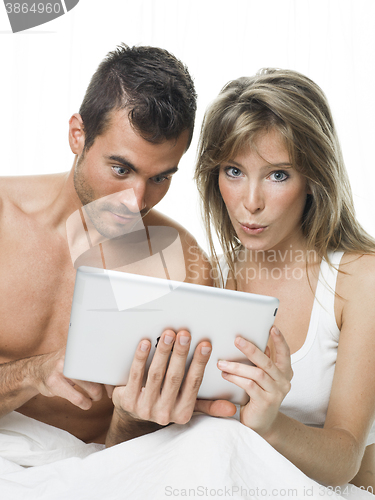 Image of attractive couple watching things in a tablet