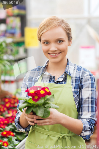 Image of happy woman holding flowers in greenhouse