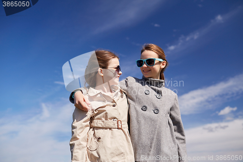 Image of happy little girls hugging and talking outdoors