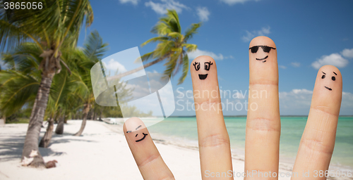 Image of close up of fingers with smiley faces on beach