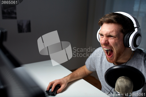 Image of man in headset playing computer video game at home