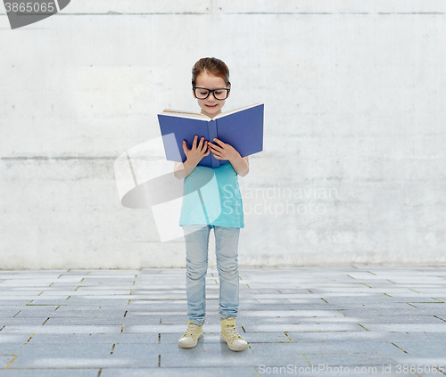 Image of happy little girl in eyeglasses reading book