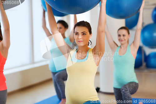 Image of happy pregnant women exercising with ball in gym