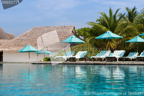 Image of parasol and sunbeds by sea on maldives beach