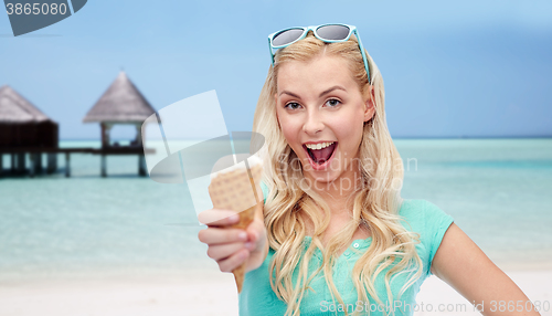 Image of happy woman in sunglasses with ice cream on beach