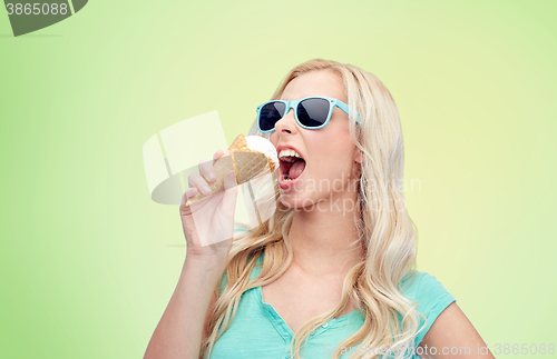 Image of happy young woman in sunglasses eating ice cream